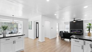A modern kitchen with white cabinets, a black countertop, and a built-in TV. - Safari Vines Retreat. Fully remodeled spacious 3 bedroom 2 bath home   
Sleeps 8 (Escondido)