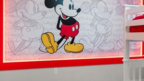 A wall with a Mickey Mouse mural and a white crib with red bedding. - Comfortable 5BR at Paradise Palms Resort (Kissimmee)