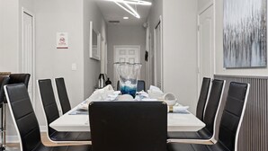 A modern dining area with a long table, black chairs, and a central decorative vase. - Comfortable 5BR at Paradise Palms Resort (Kissimmee)
