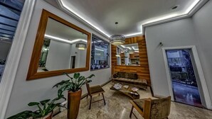 A modern interior with a large mirror, wooden panel wall, seating area, and a view through a window. - Flat Massis 133 - Bela Vista (São Paulo)
