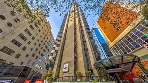 A modern building with a central tower, surrounded by other structures. - Flat Massis 133 - Bela Vista (São Paulo)