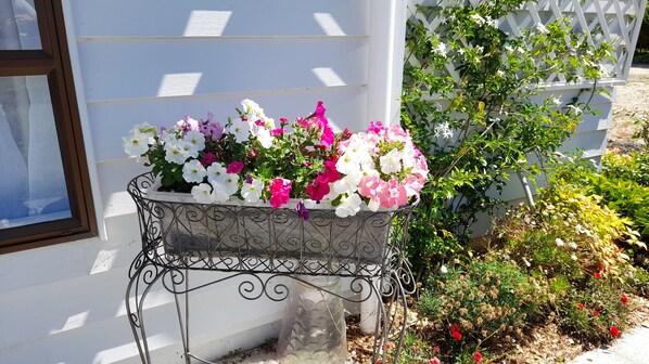 A flower pot with a variety of flowers on a metal stand outside a building. - Romantic getaway in Te Arai - Peace, Tranquility and Views (Wellsford)