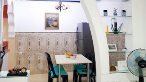 Una cucina moderna con zona pranzo, caratterizzata da un lampadario, un frigorifero e una ventola.