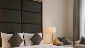 A large bed with a headboard, two bedside tables, a lamp, and two chairs. - Daif Inn Serviced Apartment - Qurtuba (Riyadh)