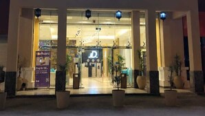 A hotel with a sign in multiple languages, including Arabic, and a large entrance with a covered walkway.