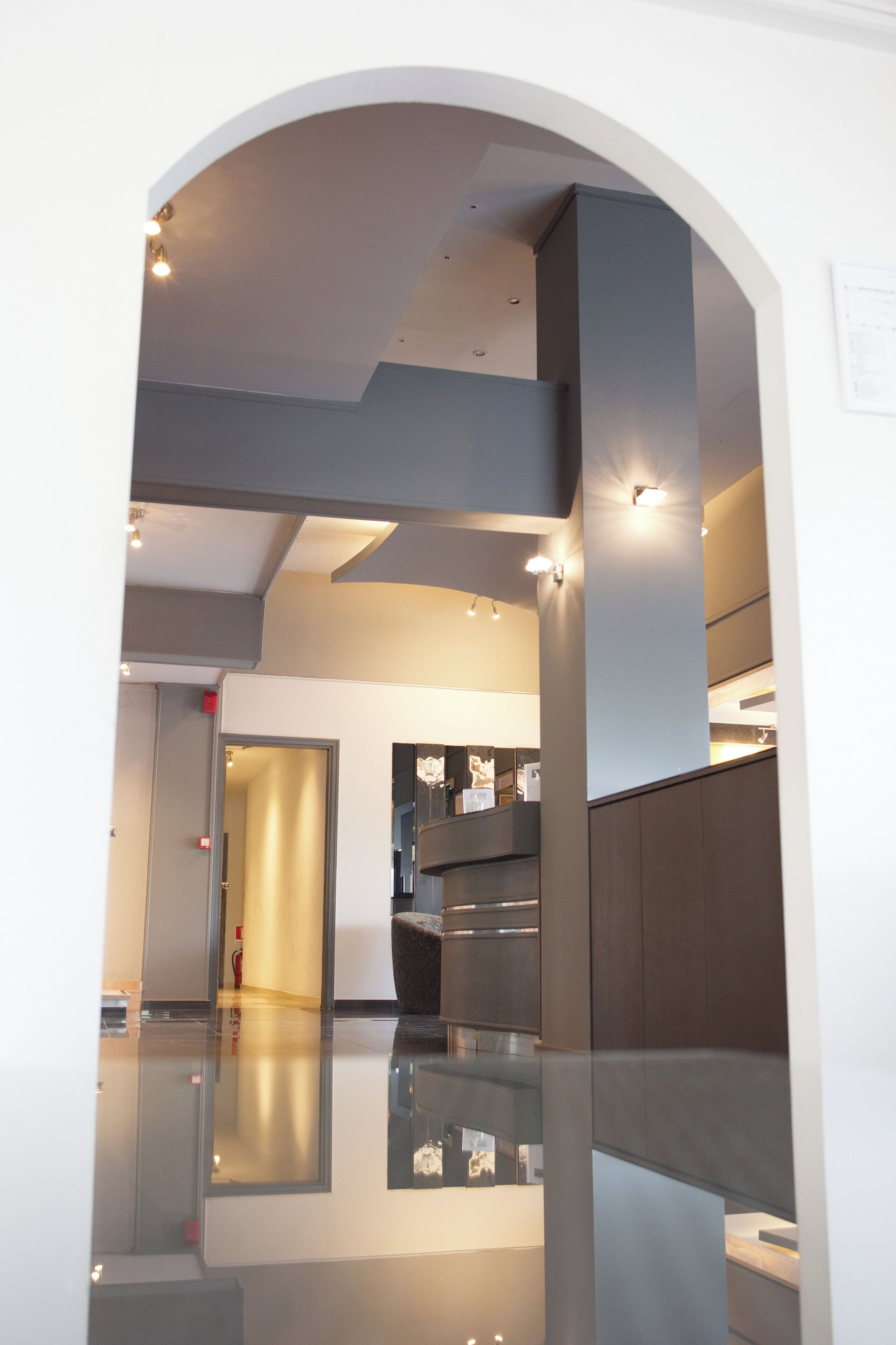 Un intérieur moderne avec une cloison en verre, un escalier et un espace d’accueil.