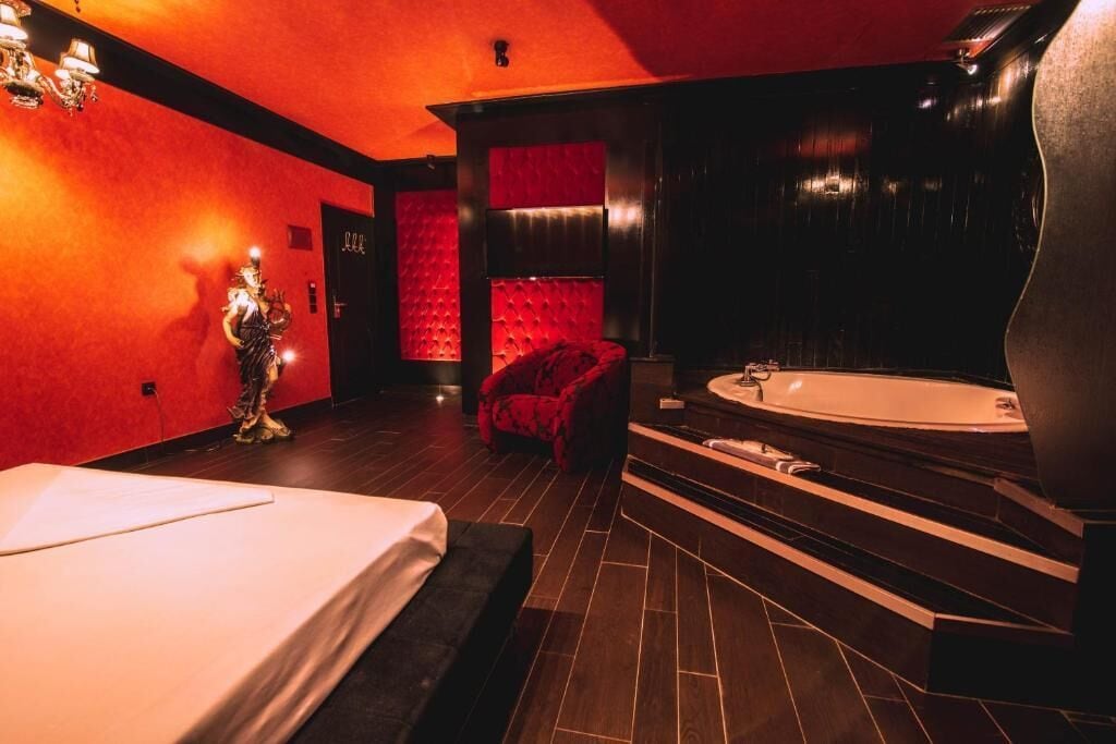 Un baño moderno con una bañera grande, una silla roja y una estatua.
