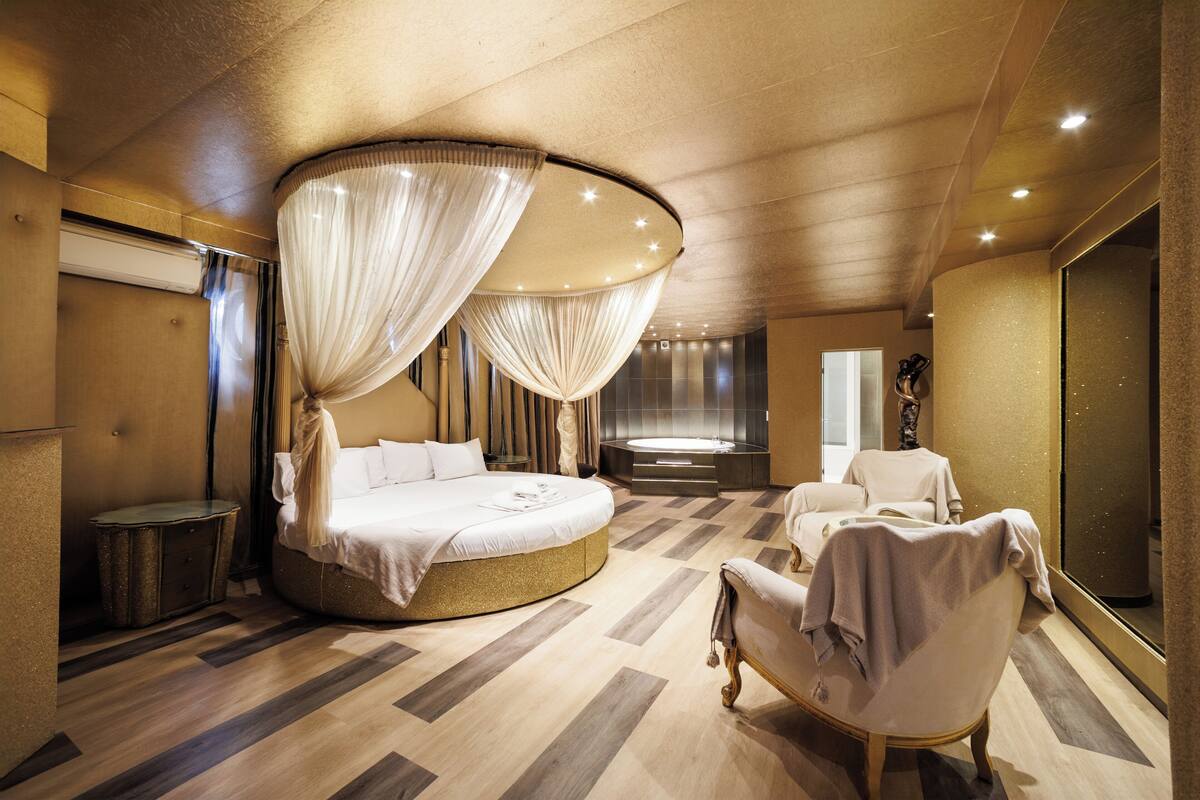 Une chambre à coucher luxueuse avec un lit rond, une baignoire et un grand miroir.