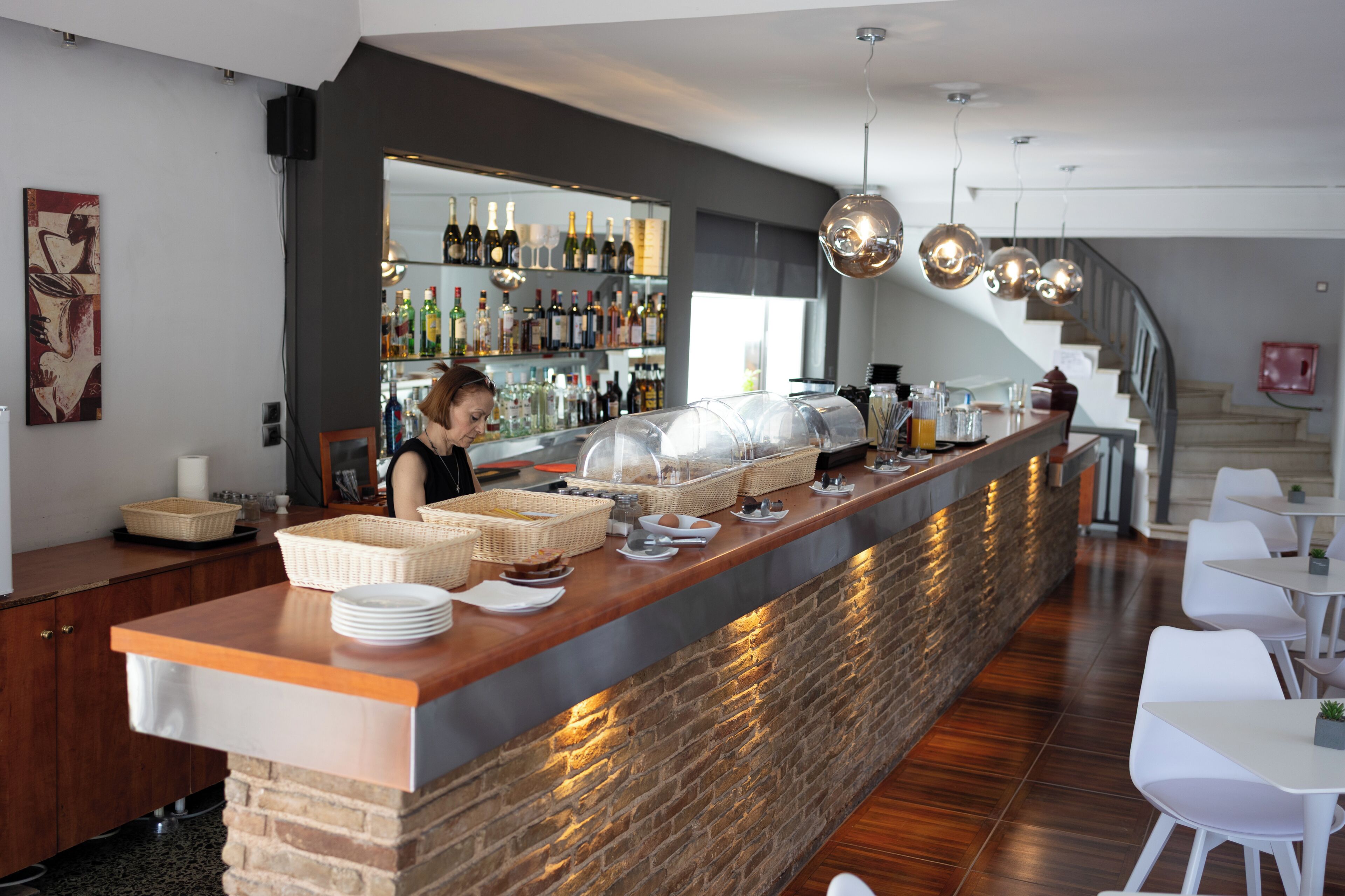 Zona de bar con mostrador, cestas, platos y una persona sirviendo detrás.