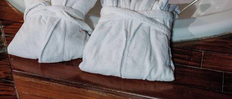 A bathroom with a bathtub, two towels, and a pair of slippers.