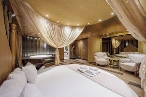 Un dormitorio lujoso con una cama grande, una zona de estar con una mesa y un baño separado con bañera.