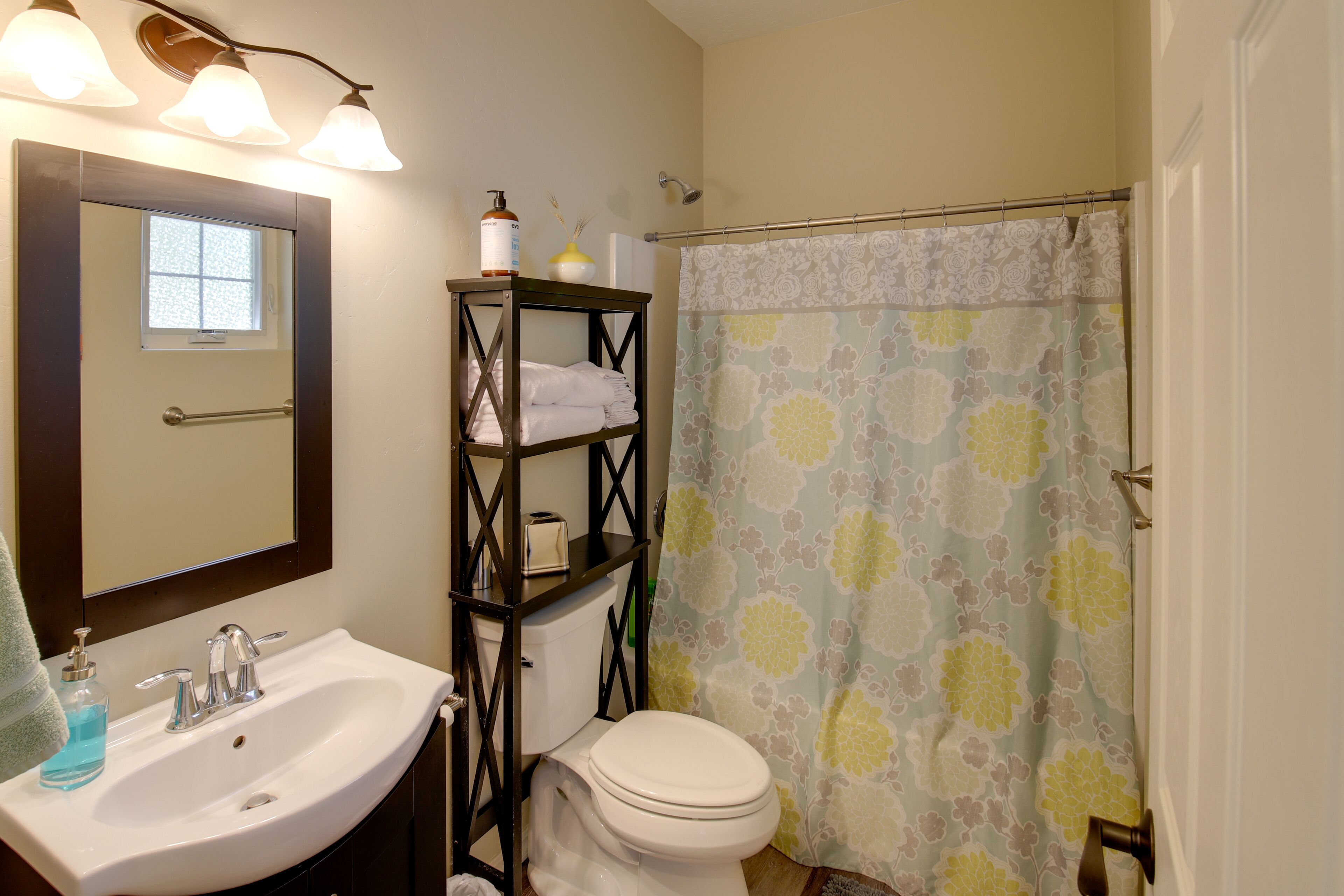 A bathroom with a white sink, a mirror, a toilet, and a shower curtain.