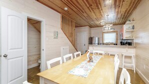 A wooden interior with a dining table, chairs, a staircase, and a kitchen area. - Resort Pool & Pet Friendly Sleeps 9 (Port Aransas)