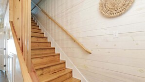 A wooden staircase with a handrail, white walls, and a woven basket on the wall. - Resort Pool & Pet Friendly Sleeps 9 (Port Aransas)