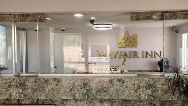 A reception area with a marble counter, a sign reading "Mayfair Inn", and a check-out time notice. - Mayfair Inn Ontario Airport (Ontario)