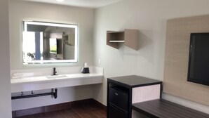 A modern bathroom with a white sink, a mirror, a black cabinet, and a wooden vanity. - Mayfair Inn Ontario Airport (Ontario)