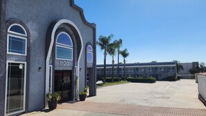 A building with a number 1120 sign, large arched windows, and a paved entrance area with potted plants. - Mayfair Inn Ontario Airport (Ontario)