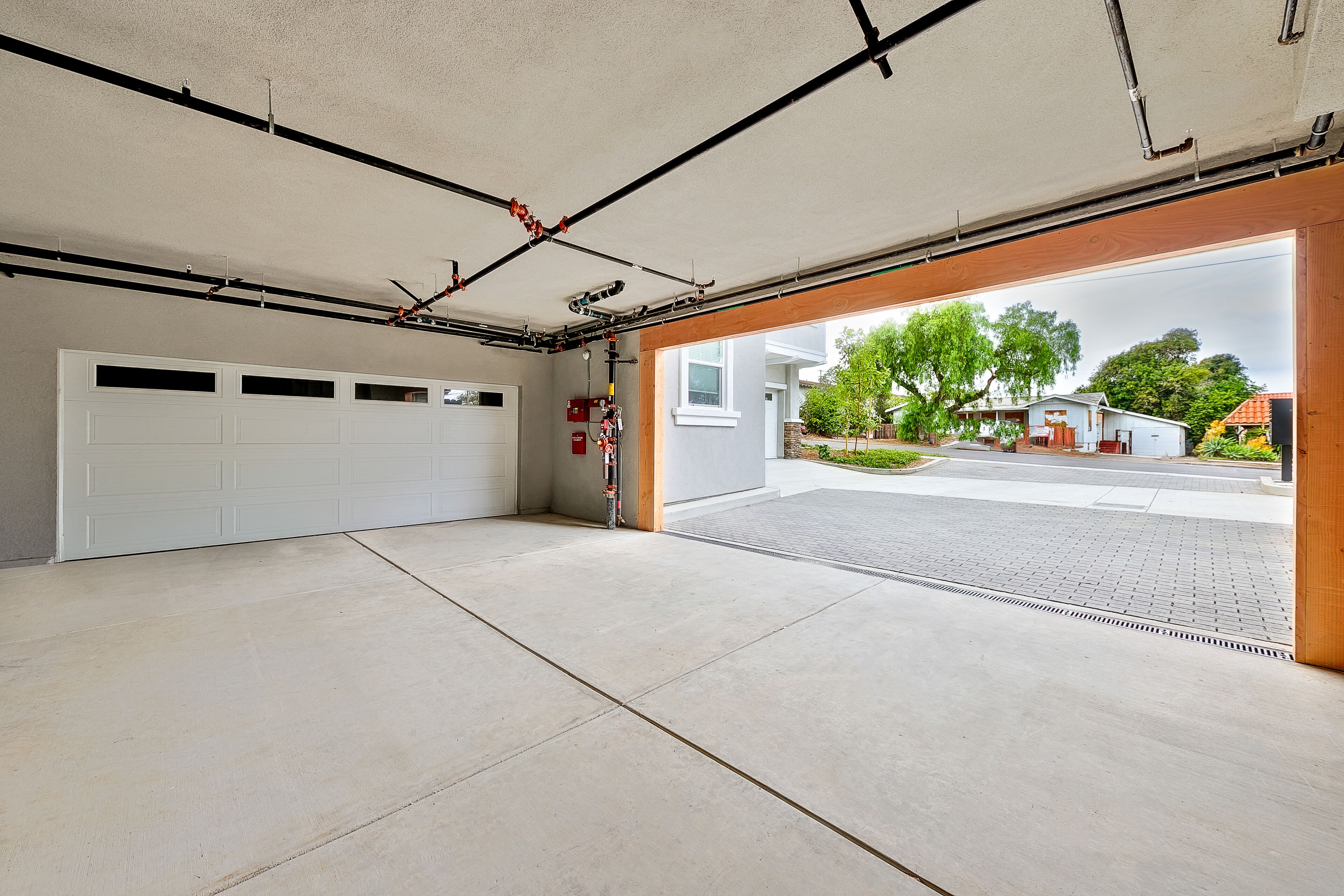 A garage with a concrete floor, a white garage door, and a wooden door leading outside.