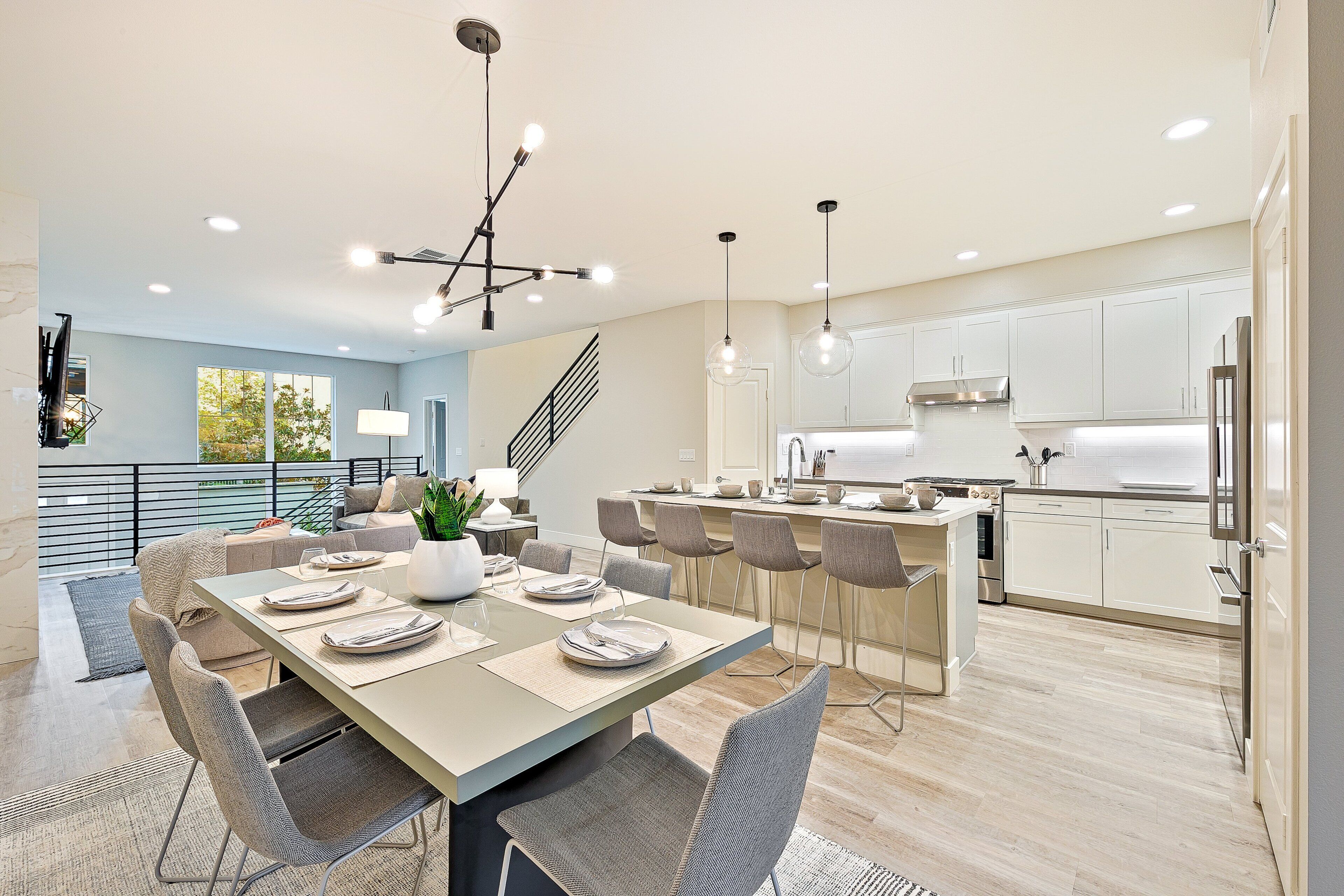 A modern kitchen with white cabinets, a stainless steel range hood, and a dining area with a table set for four.