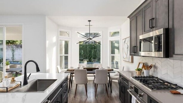 A modern kitchen with dark cabinets, a stainless steel stove, and a large window overlooking a garden. - Contemporary Home in Best location!



 (Fresno)