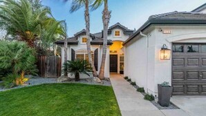 A two-story house with a well-maintained lawn, a garage, and a driveway leading to the entrance. - Contemporary Home in Best location!



 (Fresno)