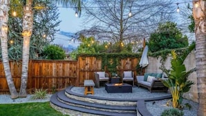 A circular outdoor seating area with a fire pit, surrounded by a stone wall and a wooden fence. - Contemporary Home in Best location!



 (Fresno)