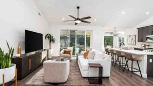 A modern living room with a sofa, a coffee table, and a TV. There is a kitchen area with a bar and stools. - Contemporary Home in Best location!



 (Fresno)