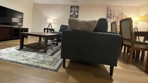 Ett vardagsrum med en soffa, ett soffbord, en tv och en lampa.