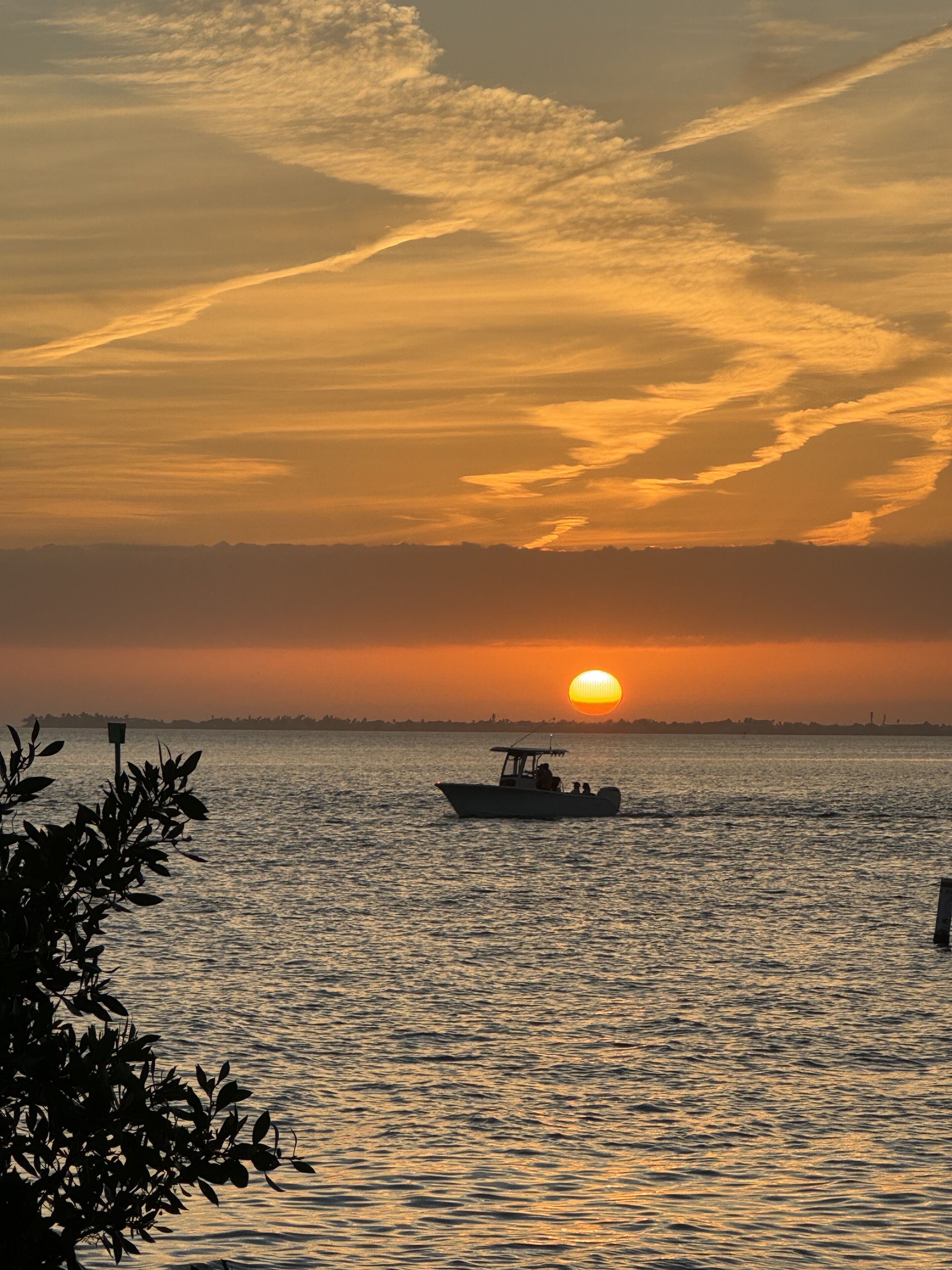 A sunset over a calm body of water with a boat in the foreground.