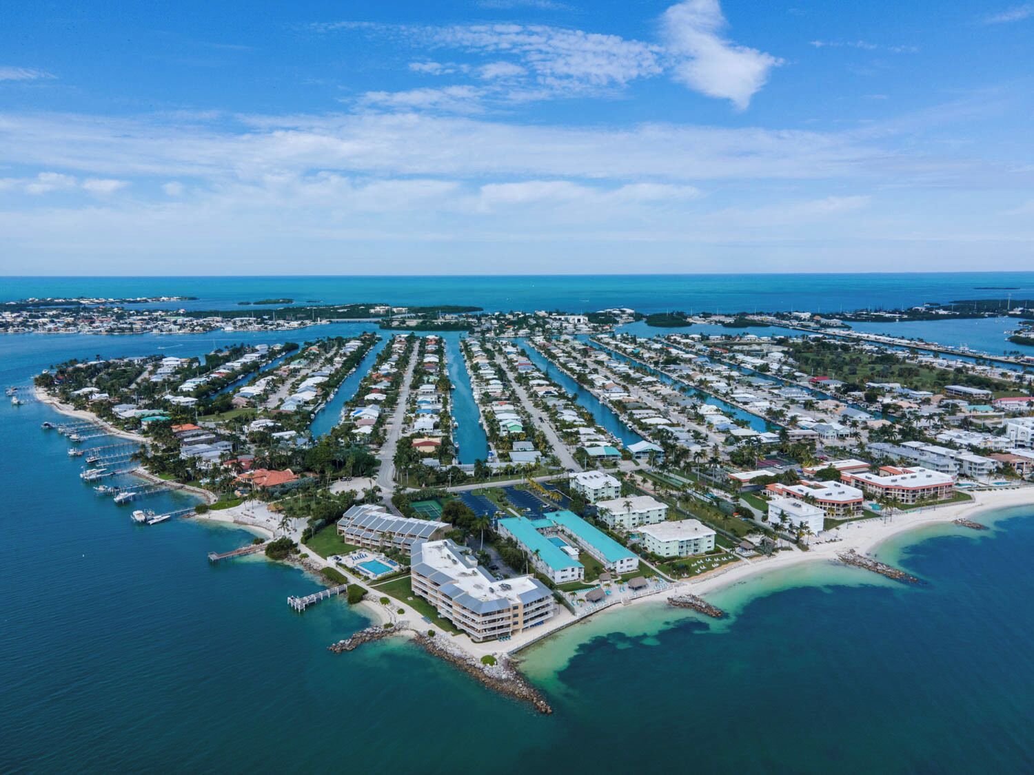 An aerial view of a coastal resort with multiple buildings, a marina, and a beach.