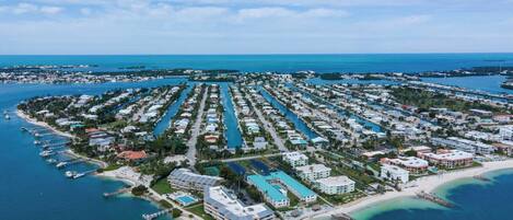 An aerial view of a coastal resort with multiple buildings, a marina, and a beach.