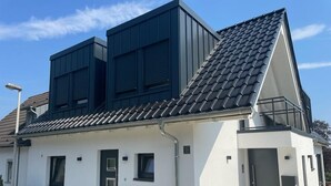 En moderne toetagers bygning med skråt tag, en lille veranda og en garage.