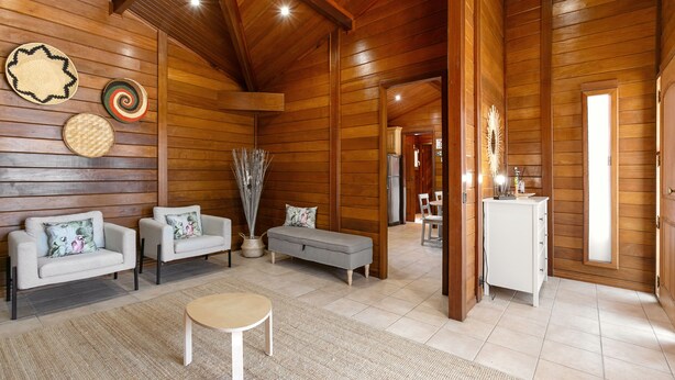 A spacious living room with a high ceiling, wooden walls, a sofa set, a coffee table, and a small cabinet. - Casa da Poesia - Private Pool (Porto de Mós)
