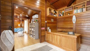 A wooden interior with a reception desk, bookshelves, a hanging chair, and a geometric light fixture. - Casa da Poesia - Private Pool (Porto de Mós)