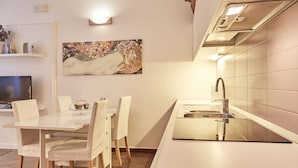 A modern kitchen with a white countertop, stainless steel sink, and a dining area with a white table and chairs.