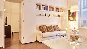 A modern living room with a sofa, a glass coffee table, and a bookshelf.