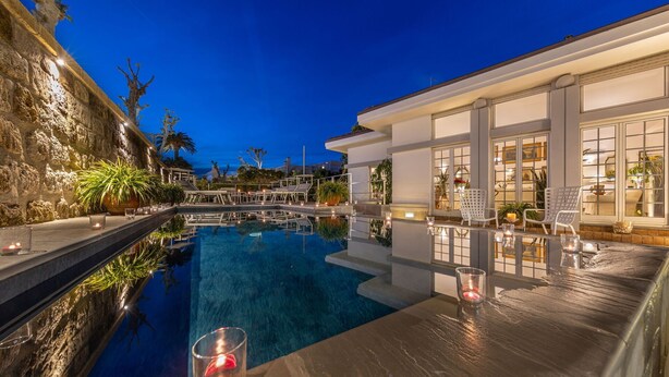 A luxurious pool area with a clear view of the pool, lounge chairs, and a bar area with candles.