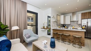 A modern kitchen with a marble countertop, stainless steel appliances, and a bar area with stools.