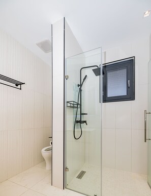 A modern bathroom with a glass-enclosed shower, a toilet, and a towel rack. - Wariruri 2-22 BRAND NEW Apartment, private balcony! (Noord)