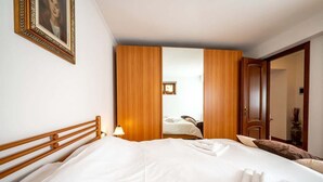 A hotel room with a large bed, wooden wardrobe, and a framed picture on the wall. - Lakefront Haven: Apartment w/ Balcony & Bike A24 by Larihome (Dongo)
