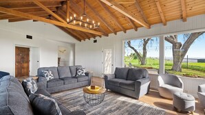 Un salon spacieux avec un plafond haut et de grandes fenêtres donnant sur l’extérieur.