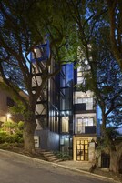 Un edificio moderno con varios pisos, ventanas amplias y una escalera que conduce a la entrada.