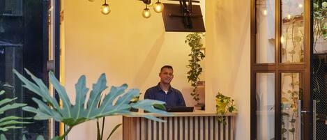 A reception desk with a modern design, a sign above it, and a potted plant.