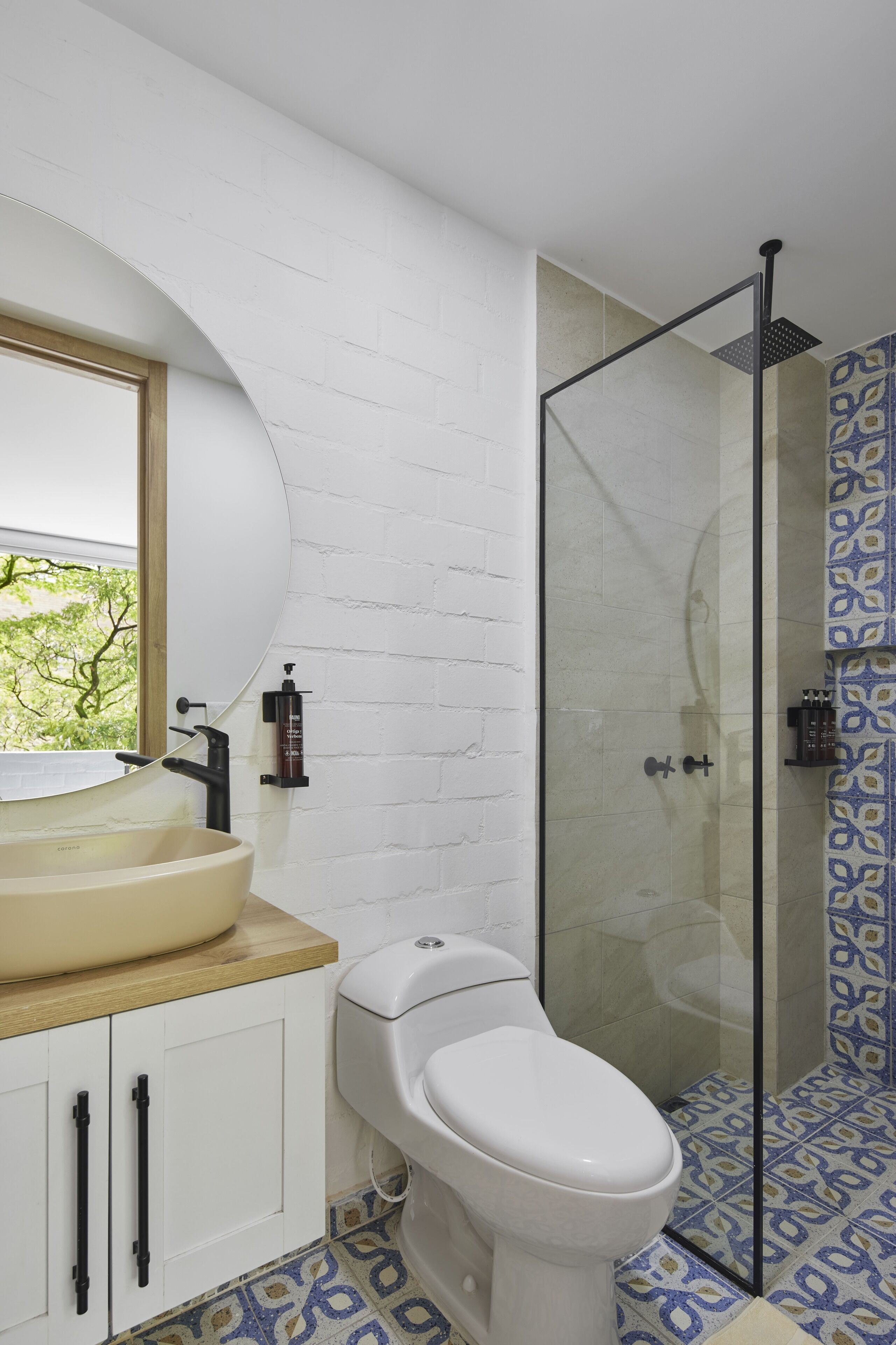 Un baño con lavamanos blanco, inodoro y ducha con mampara de vidrio.