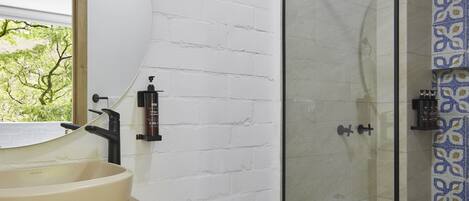 Un baño con lavamanos blanco, inodoro y ducha con mampara de vidrio.