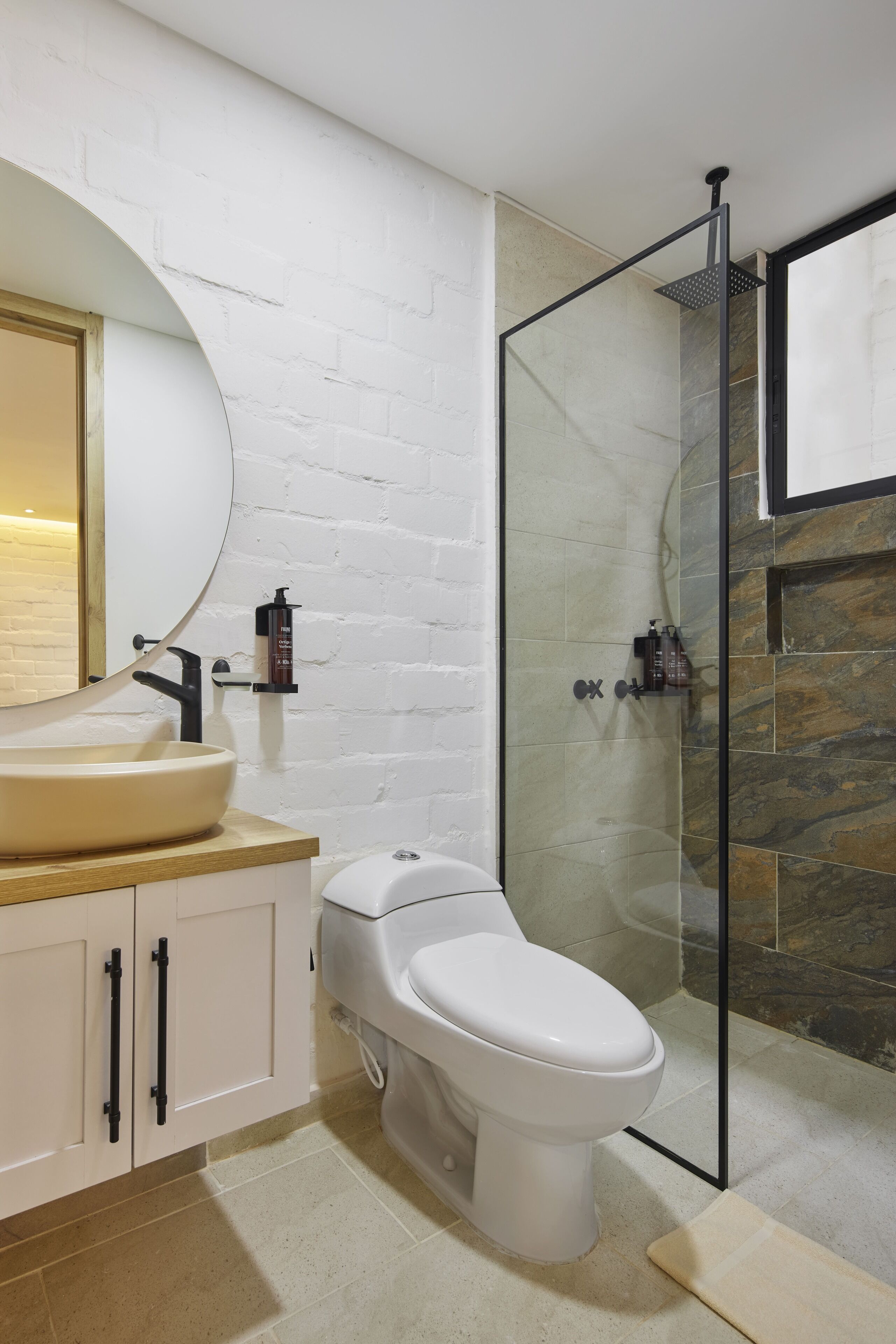 A modern bathroom with a white sink, a toilet, and a glass-enclosed shower.