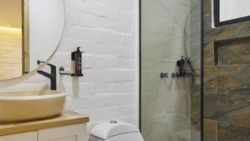 A modern bathroom with a white sink, a toilet, and a glass-enclosed shower.