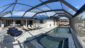Ein Schwimmbad mit Glasveranda, Liegestühlen und überdachter Terrasse.