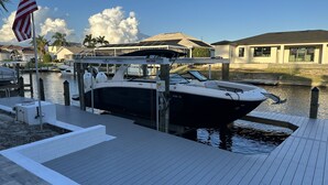 Ein Steg mit einem Boot, eine Marina und Häuser im Hintergrund.