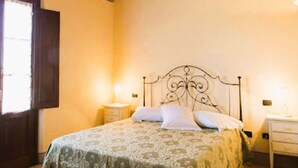 Une chambre à coucher avec un lit, deux tables de chevet et une fenêtre avec des rideaux.